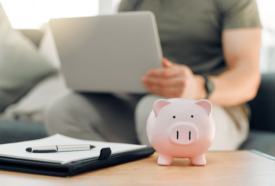 man-searching-banks-on-laptop-with-piggy-bank-on-table