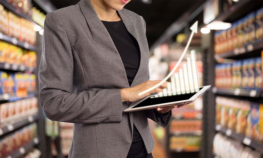 woman in market looking at tablet seeing chart of sales increase